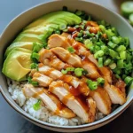 Chicken Rice Bowl with juicy sliced chicken, fresh avocado, green onions, and a drizzle of savory sauce over fluffy white rice.