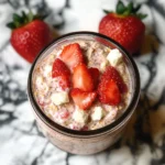 Creamy Strawberries and Cream Overnight Oats in a glass jar with fresh berry toppings