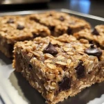 Close-up of golden Baked Oatmeal Bars with a rustic texture and oatmeal topping.