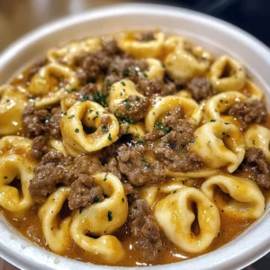 A close-up of Cheesesteak Tortellini with melted provolone, steak slices, and bell peppers in a rich, creamy sauce.