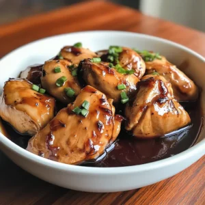 A close-up of Crockpot Bourbon Chicken coated in a thick, glossy bourbon sauce, served on a plate with a side of stir-fried vegetables.